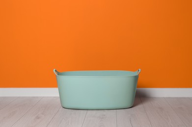 Laundry basket with handles near orange wall indoors, space for text Photo of Laundry basket with handles near orange wall indoors, space for text