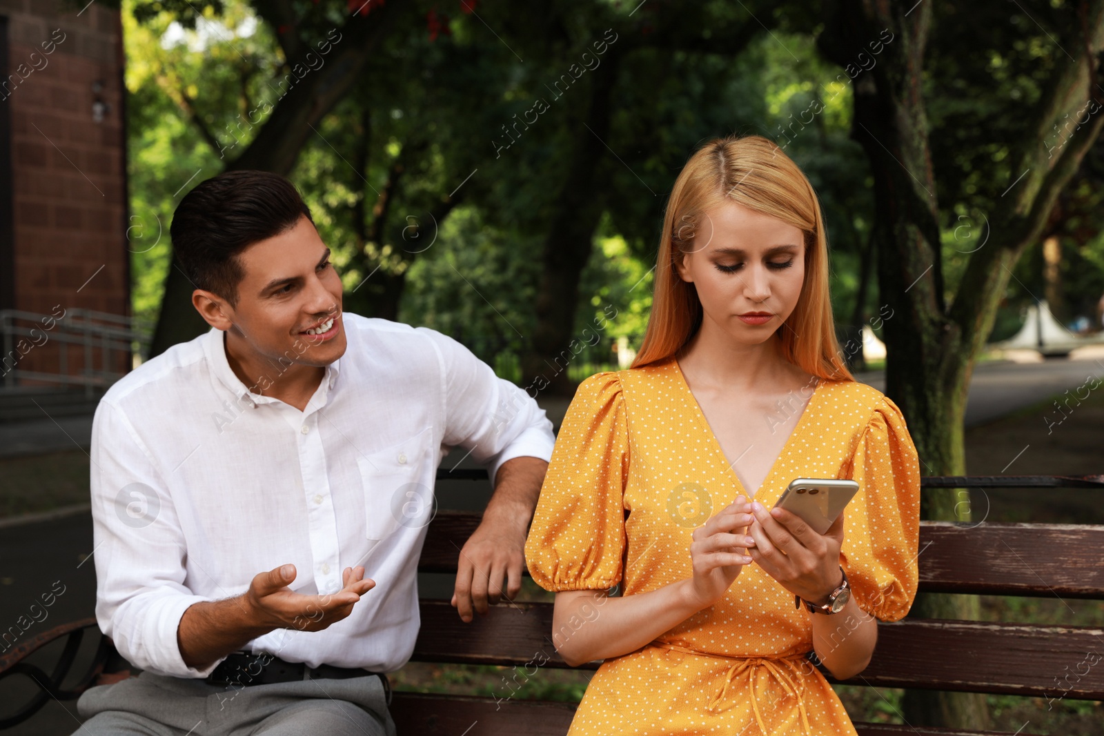Young woman with smartphone ignoring her boyfriend in park. Boring date Photo of Young woman with smartphone ignoring her boyfriend in park. Boring date