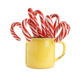 Yellow cup with sweet Christmas candy canes isolated on white Photo of Yellow cup with sweet Christmas candy canes isolated on white