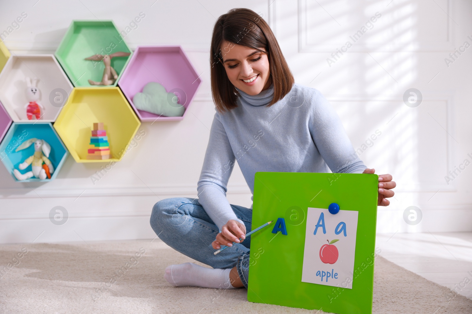 Happy female English teacher giving lesson indoors. Early childhood education Photo of Happy female English teacher giving lesson indoors. Early childhood education
