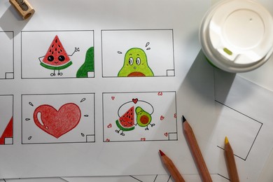 Photo of Storyboard with cartoon sketches at workplace, flat lay. Pre-production process