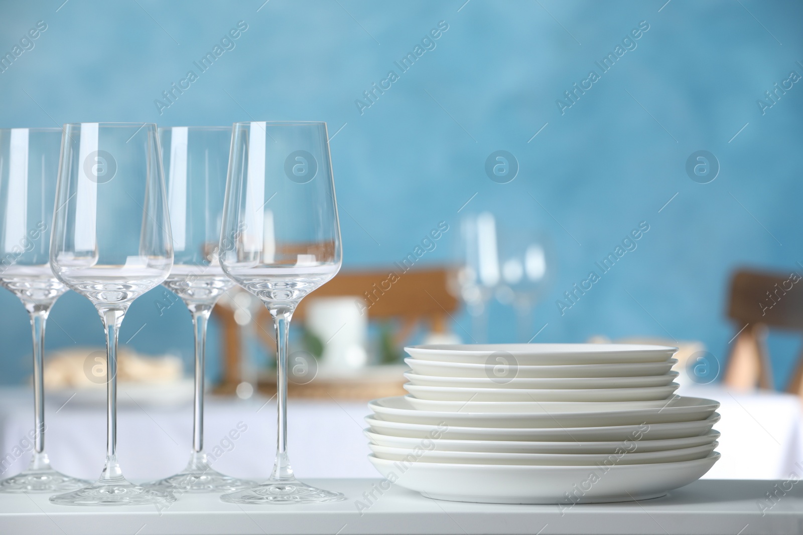 Stacked clean dishes and glasses on white shelf indoors Photo of Stacked clean dishes and glasses on white shelf indoors