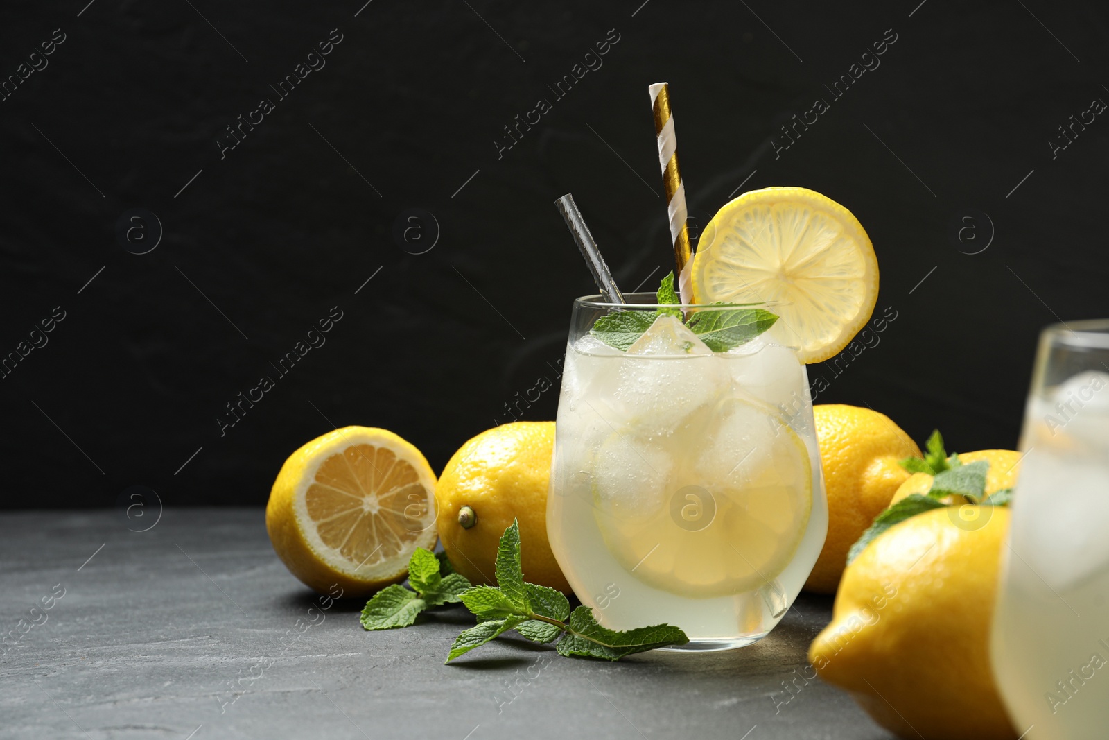 Natural lemonade with mint on grey table against black background, space for text. Summer refreshing drink Photo of Natural lemonade with mint on grey table against black background, space for text. Summer refreshing drink