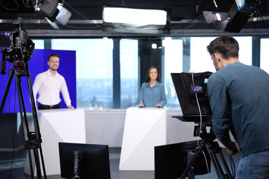 Photo of Presenters and video camera operator working in studio. News broadcasting
