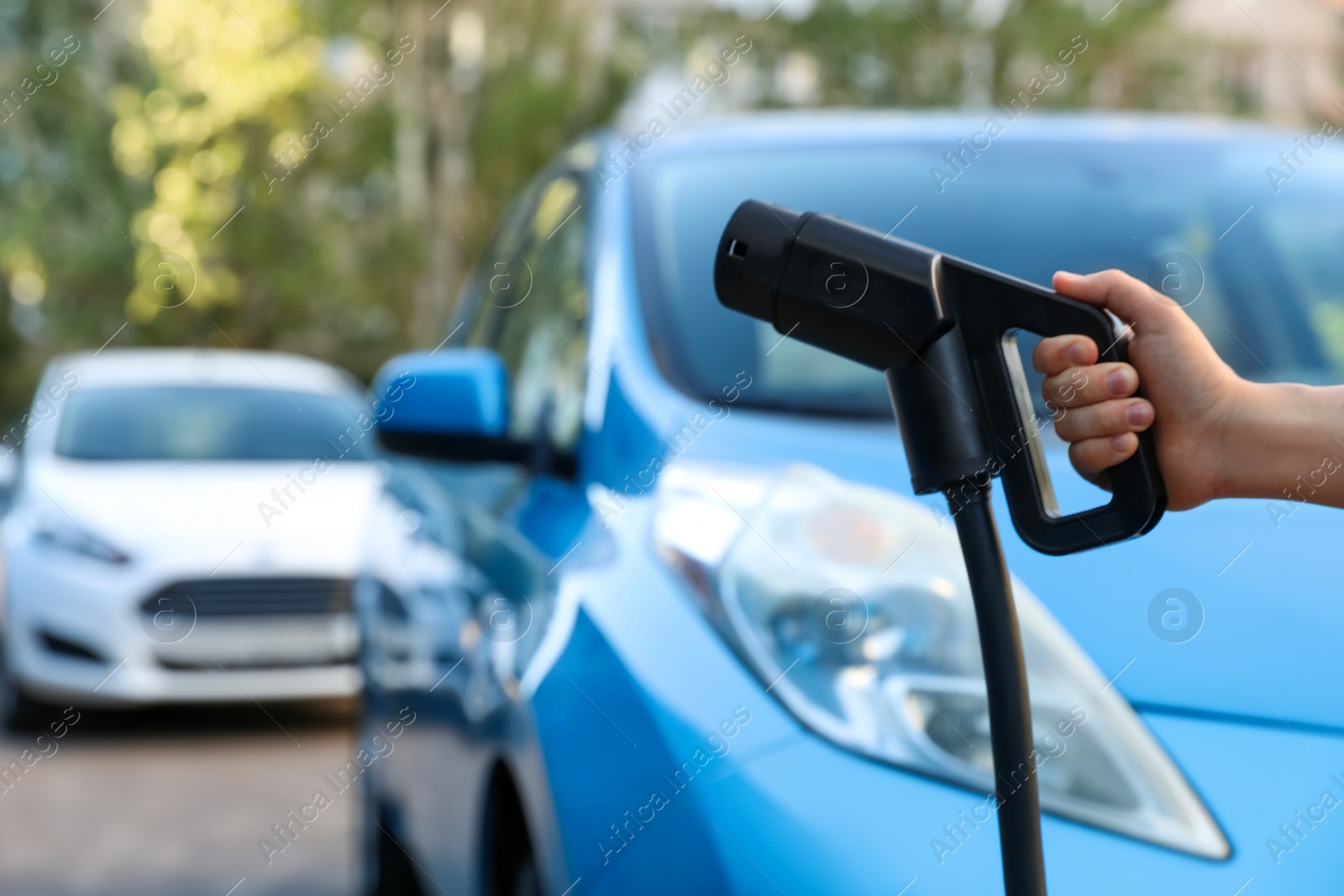 Woman holding power supply cable at electric vehicle charging station, closeup Photo of Woman holding power supply cable at electric vehicle charging station, closeup