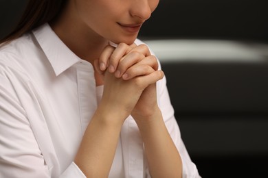 Religious woman with clasped hands praying indoors, closeup Photo of Religious woman with clasped hands praying indoors, closeup