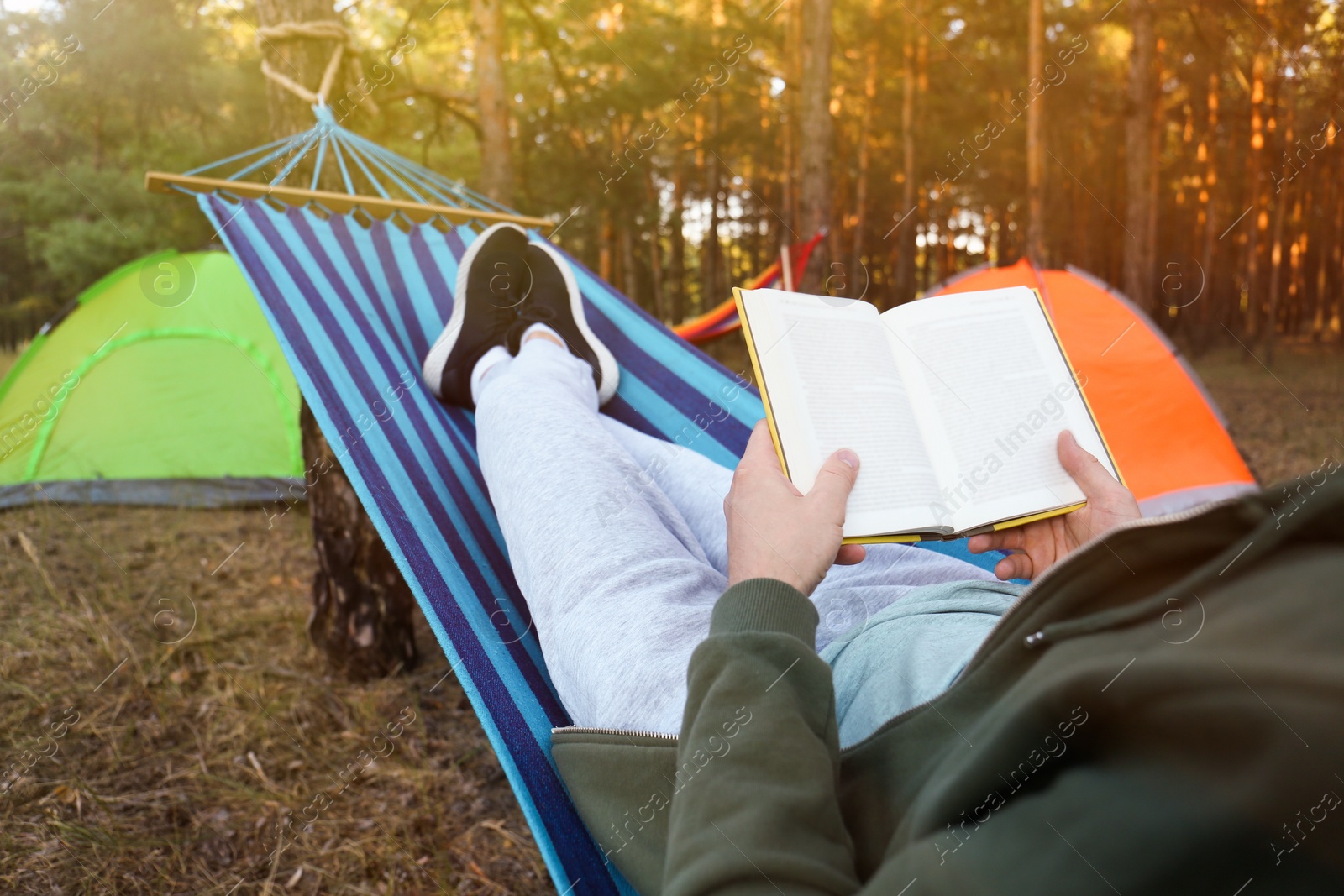 Man with book resting in comfortable hammock outdoors, closeup Photo of Man with book resting in comfortable hammock outdoors, closeup