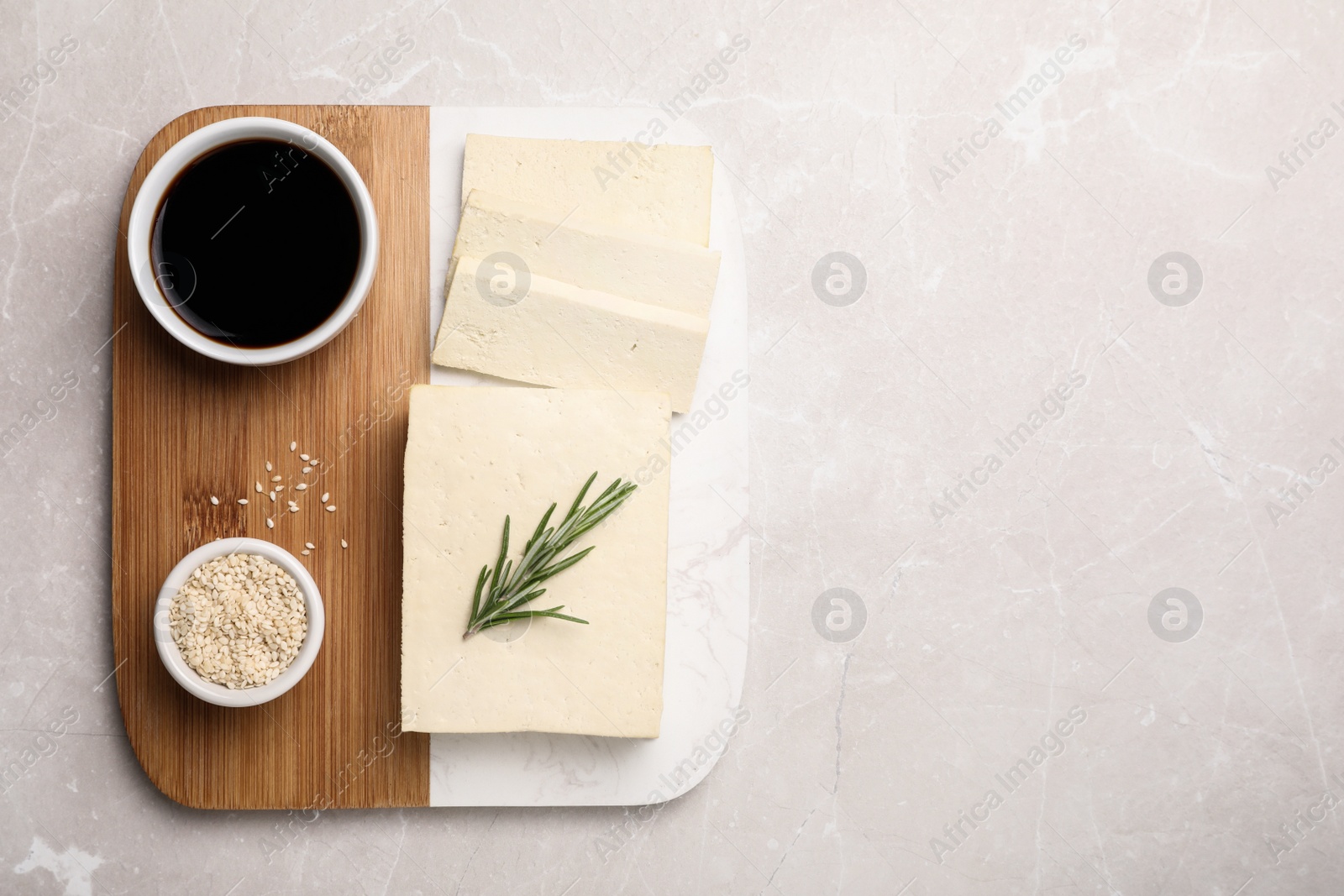 Delicious tofu with rosemary, sesame seeds and soy sauce on light table, top view. Space for text Photo of Delicious tofu with rosemary, sesame seeds and soy sauce on light table, top view. Space for text