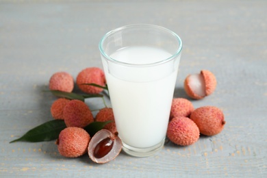Photo of Fresh lychee juice and fruits on grey wooden table