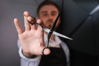Hairdresser near dark wall, focus on professional scissors Photo of Hairdresser near dark wall, focus on professional scissors