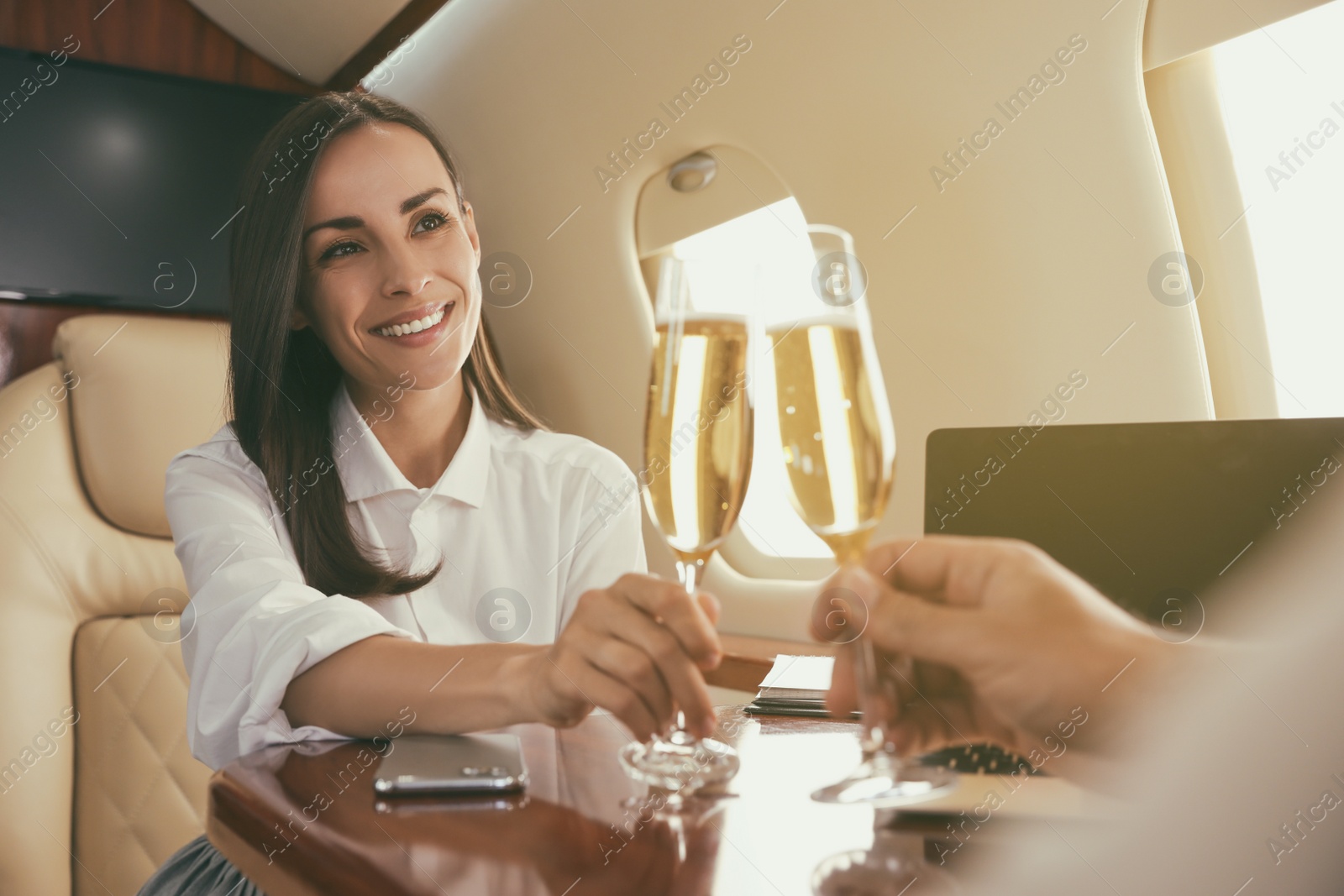 Colleagues clinking glasses of champagne at table in airplane during flight Photo of Colleagues clinking glasses of champagne at table in airplane during flight