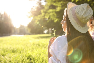 Young woman with flower outdoors on sunny day, space for text Photo of Young woman with flower outdoors on sunny day, space for text
