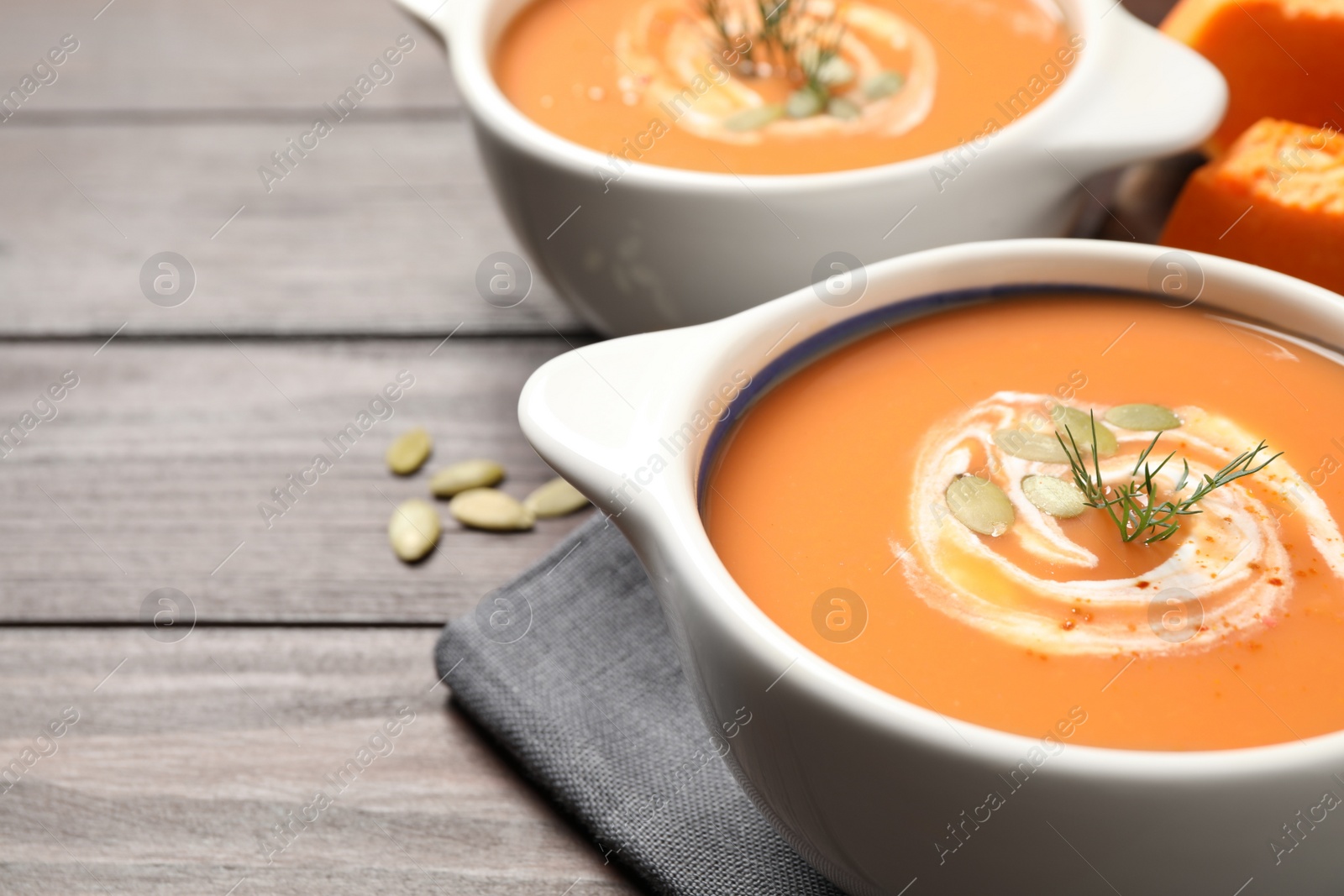 Tasty creamy pumpkin soup with dill and seeds in bowl on wooden table. Space for text Photo of Tasty creamy pumpkin soup with dill and seeds in bowl on wooden table. Space for text