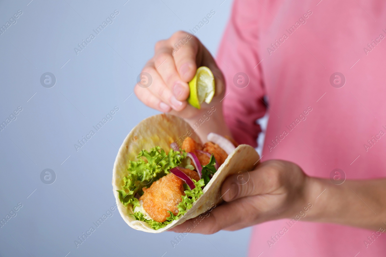 Woman squeezing lime on fish taco against grey background, closeup Photo of Woman squeezing lime on fish taco against grey background, closeup