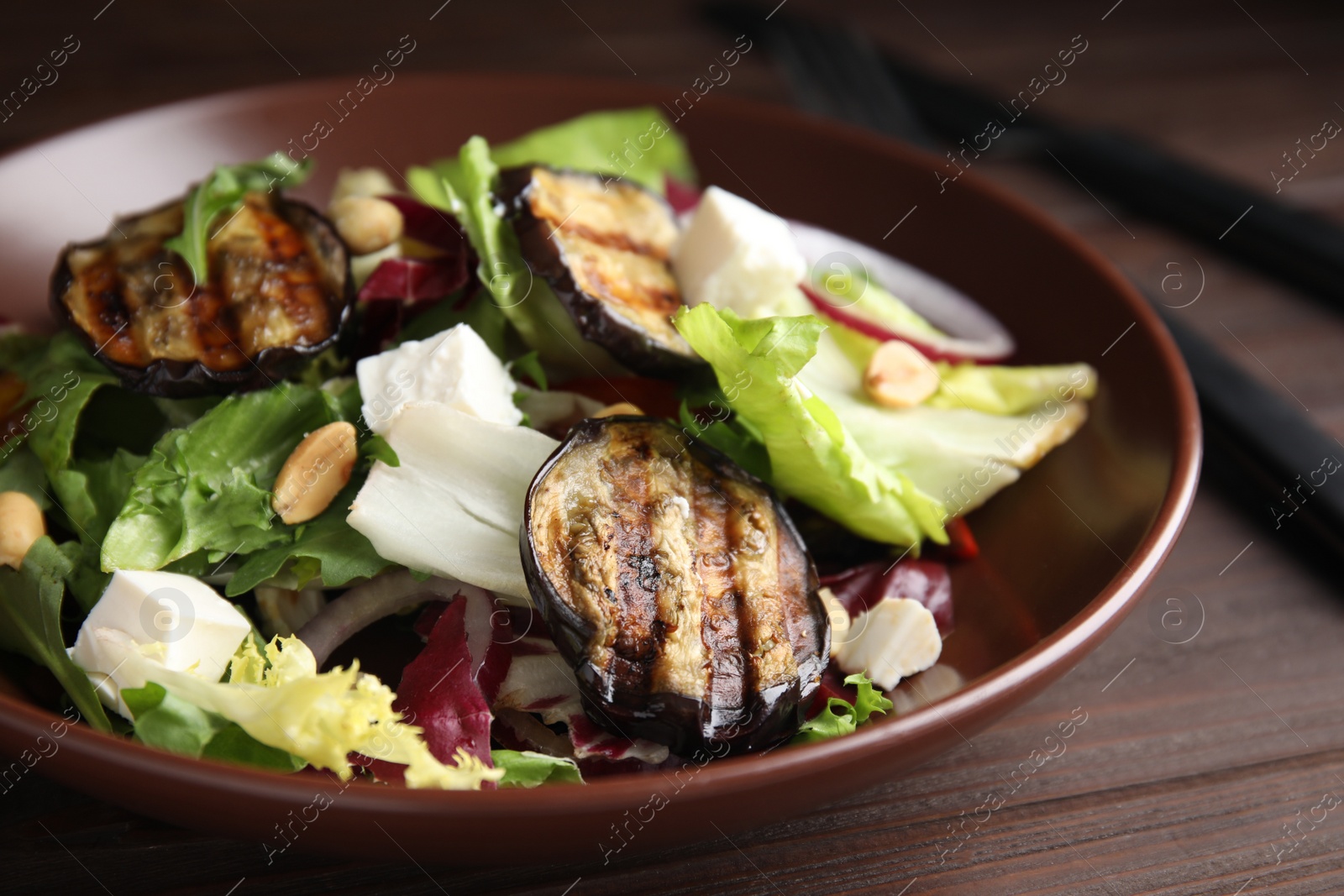 Delicious salad with roasted eggplant, feta cheese and arugula on wooden table, closeup Photo of Delicious salad with roasted eggplant, feta cheese and arugula on wooden table, closeup