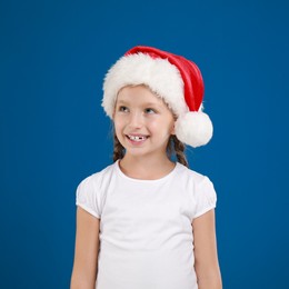 Happy little child in Santa hat on blue background. Christmas celebration Image of Happy little child in Santa hat on blue background. Christmas celebration