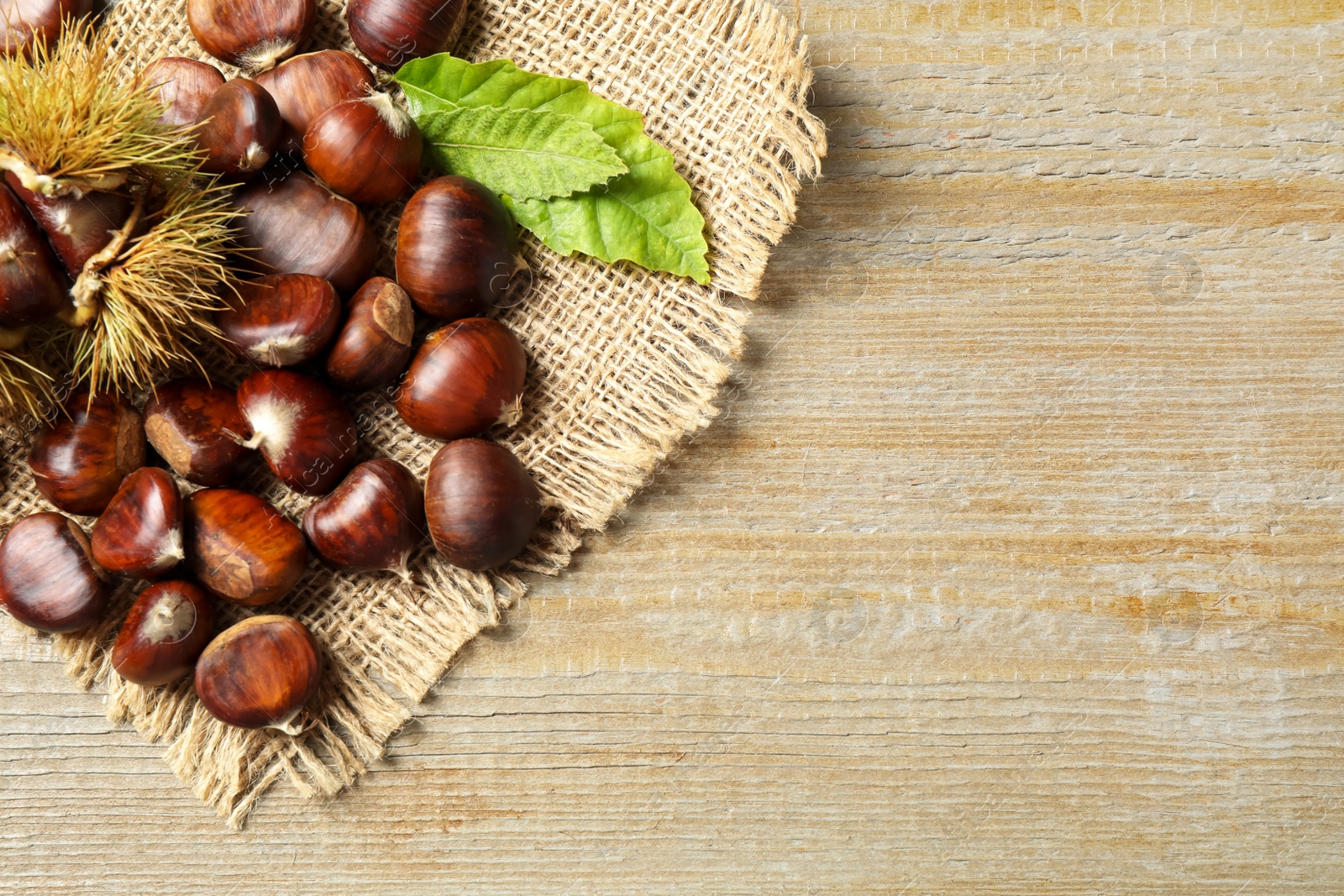 Fresh sweet edible chestnuts on wooden table, flat lay. Space for text Photo of Fresh sweet edible chestnuts on wooden table, flat lay. Space for text