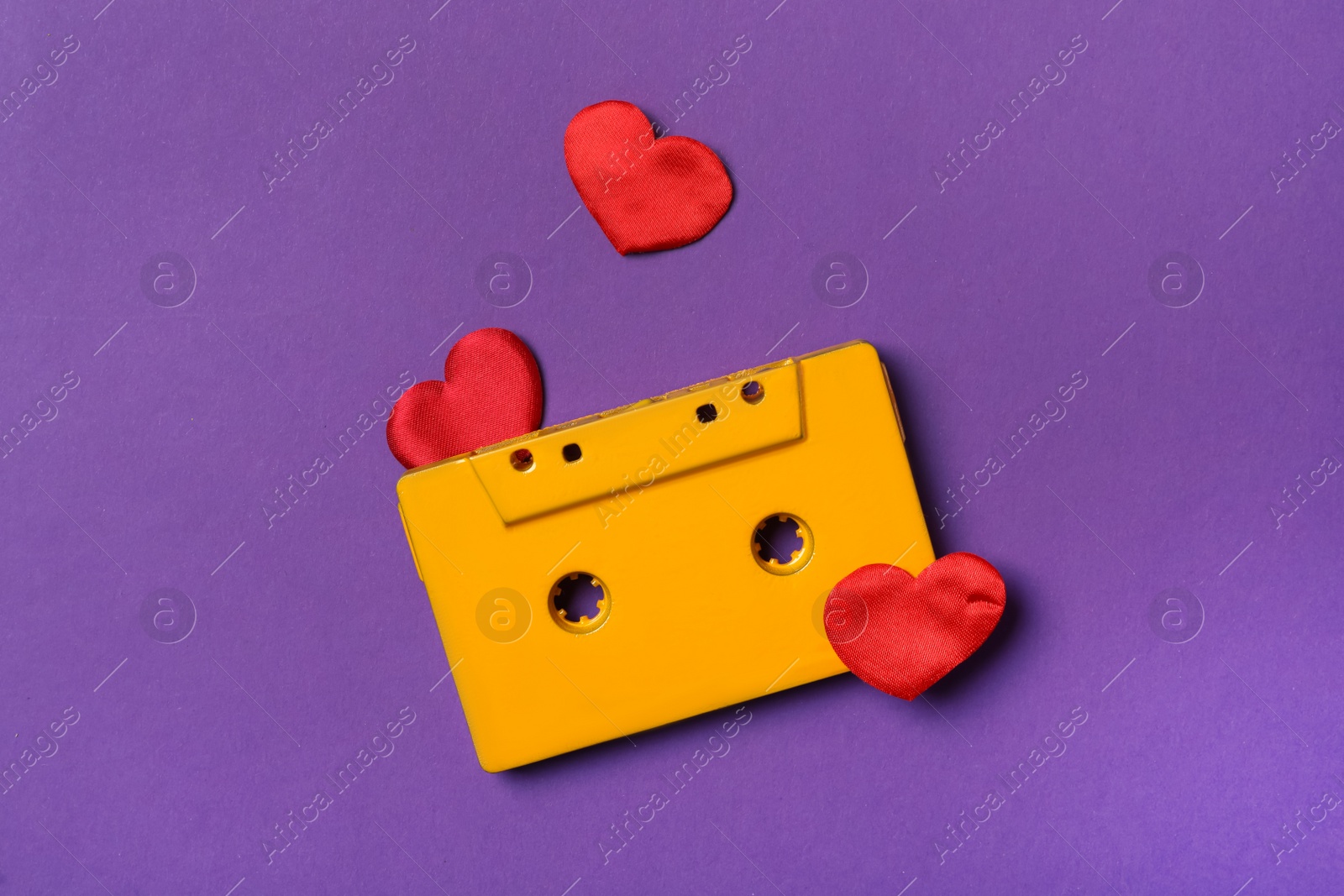 Music cassette and red hearts on purple background, flat lay. Listening love song Photo of Music cassette and red hearts on purple background, flat lay. Listening love song