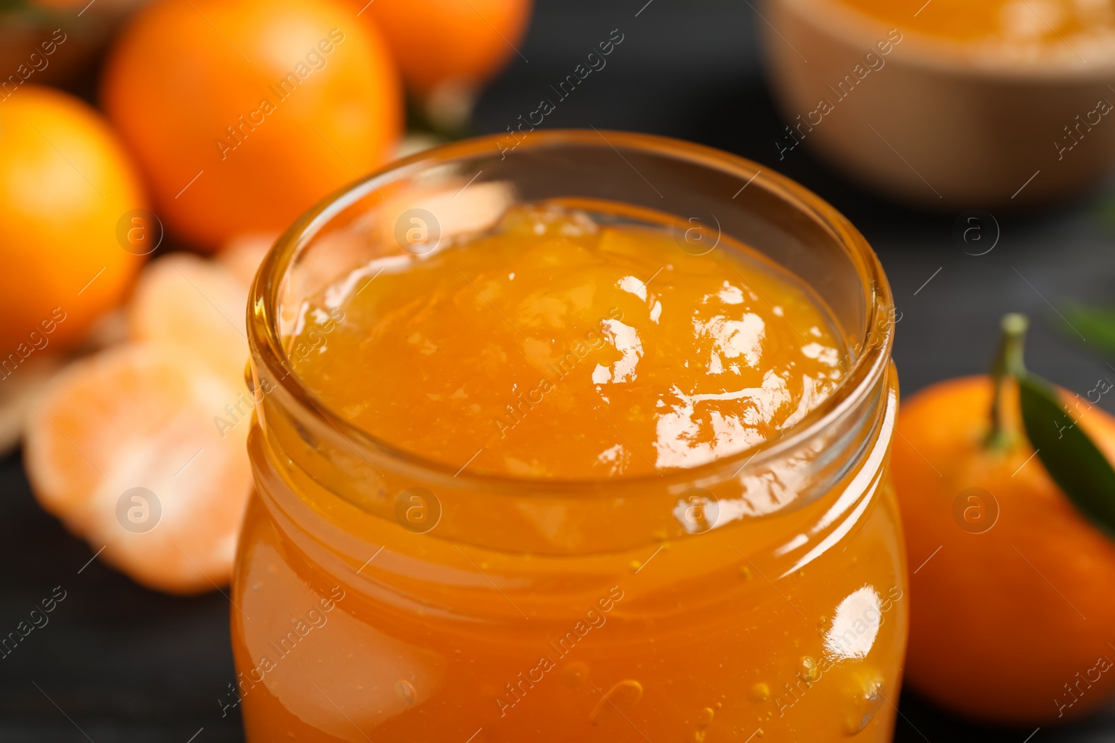 Tasty tangerine jam in glass jar on table, closeup Photo of Tasty tangerine jam in glass jar on table, closeup
