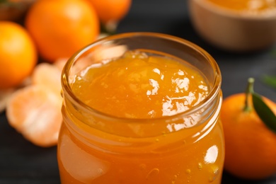 Tasty tangerine jam in glass jar on table, closeup Photo of Tasty tangerine jam in glass jar on table, closeup