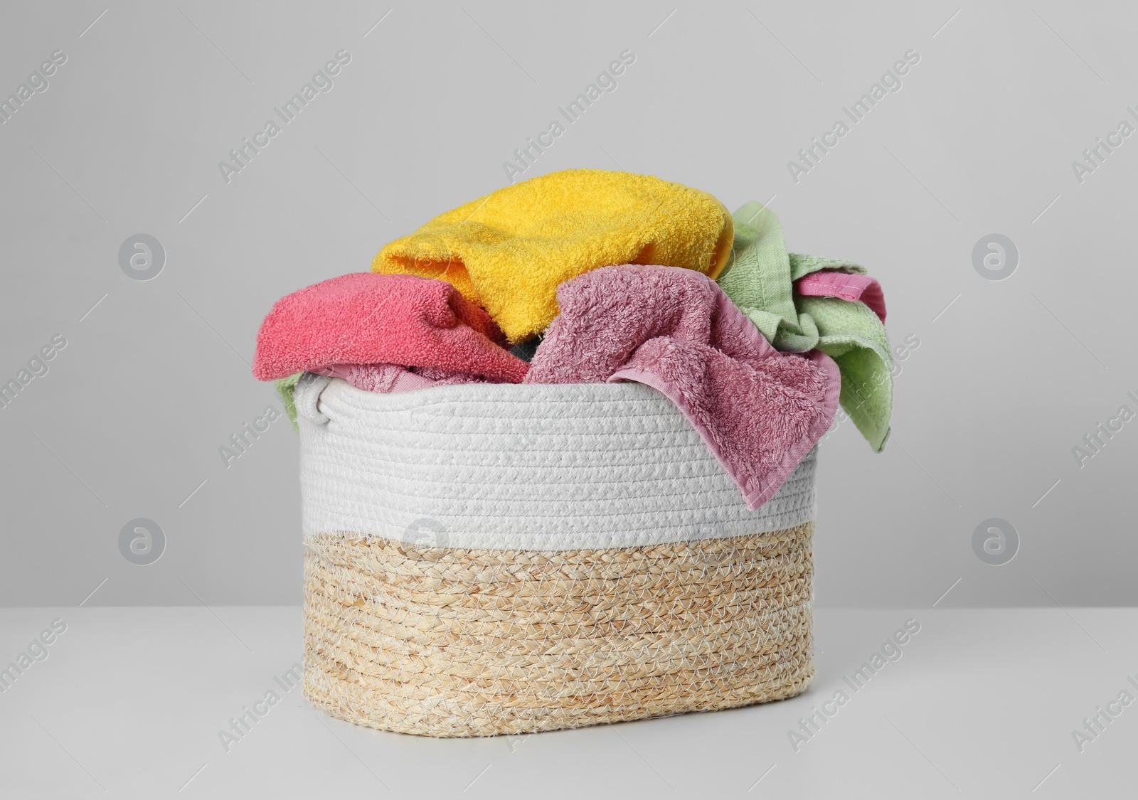 Wicker laundry basket with towels on light background Photo of Wicker laundry basket with towels on light background