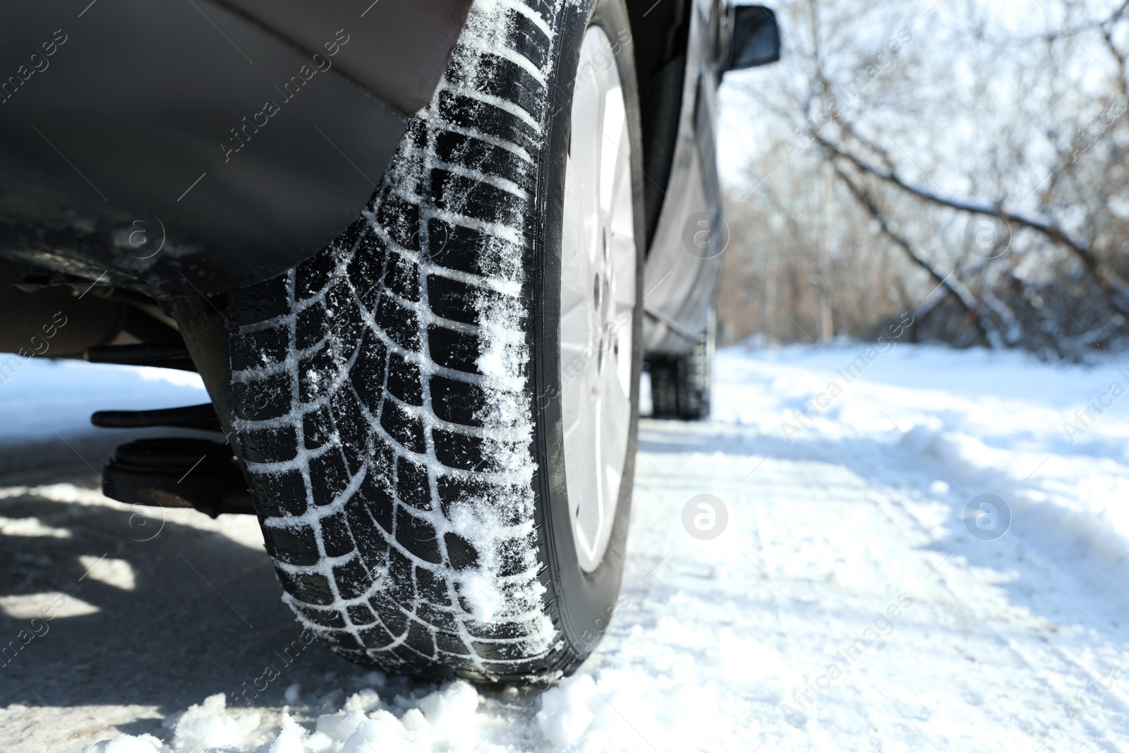 Car with winter tires on snowy road, closeup view. Space for text Photo of Car with winter tires on snowy road, closeup view. Space for text