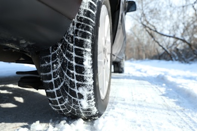 Car with winter tires on snowy road, closeup view. Space for text Photo of Car with winter tires on snowy road, closeup view. Space for text