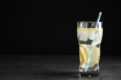 Soda water with lemon slices and ice cubes on grey table. Space for text Photo of Soda water with lemon slices and ice cubes on grey table. Space for text