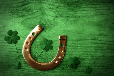 Clover leaves and horseshoe on green wooden table, flat lay. St. Patrick's Day celebration Image of Clover leaves and horseshoe on green wooden table, flat lay. St. Patrick's Day celebration