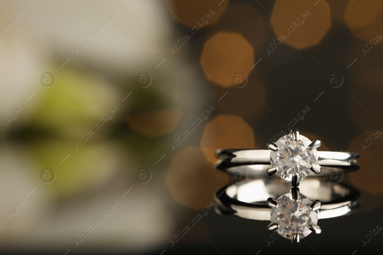 Beautiful engagement ring against blurred festive lights, closeup. Space for text Photo of Beautiful engagement ring against blurred festive lights, closeup. Space for text