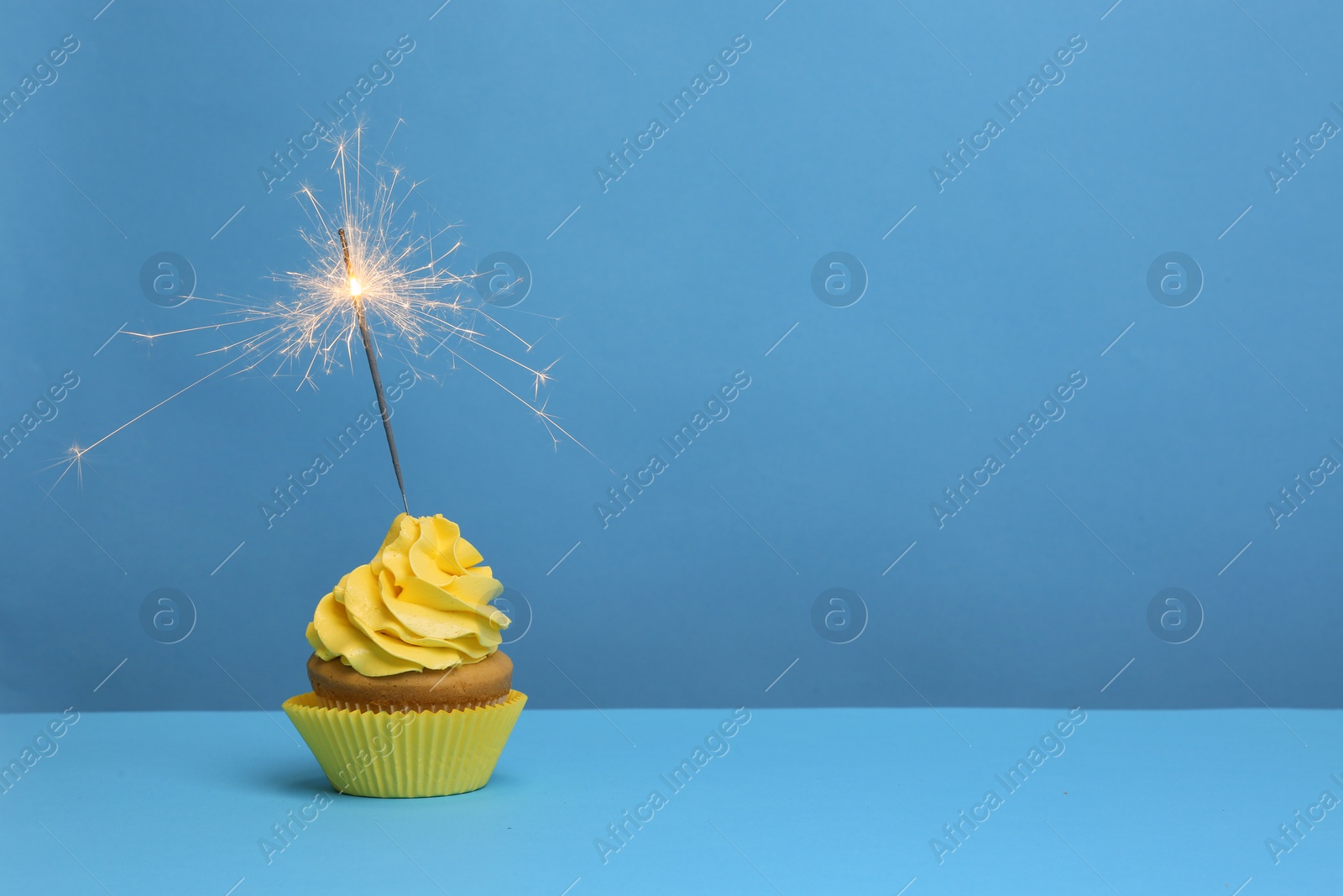 Birthday cupcake with sparkler on color background Photo of Birthday cupcake with sparkler on color background