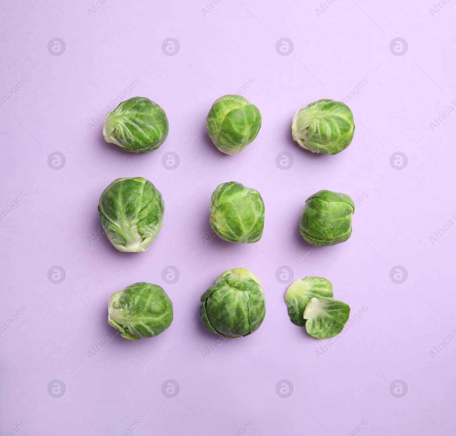 Fresh Brussels sprouts on violet background, flat lay Photo of Fresh Brussels sprouts on violet background, flat lay