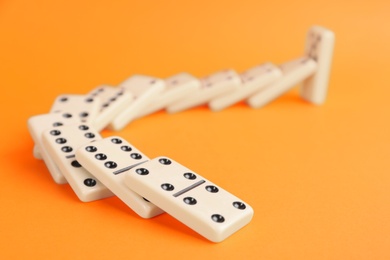 White domino tiles falling on orange background Photo of White domino tiles falling on orange background