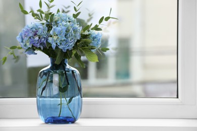 Beautiful blue hortensia flowers in vase on window sill indoors. Space for text Photo of Beautiful blue hortensia flowers in vase on window sill indoors. Space for text