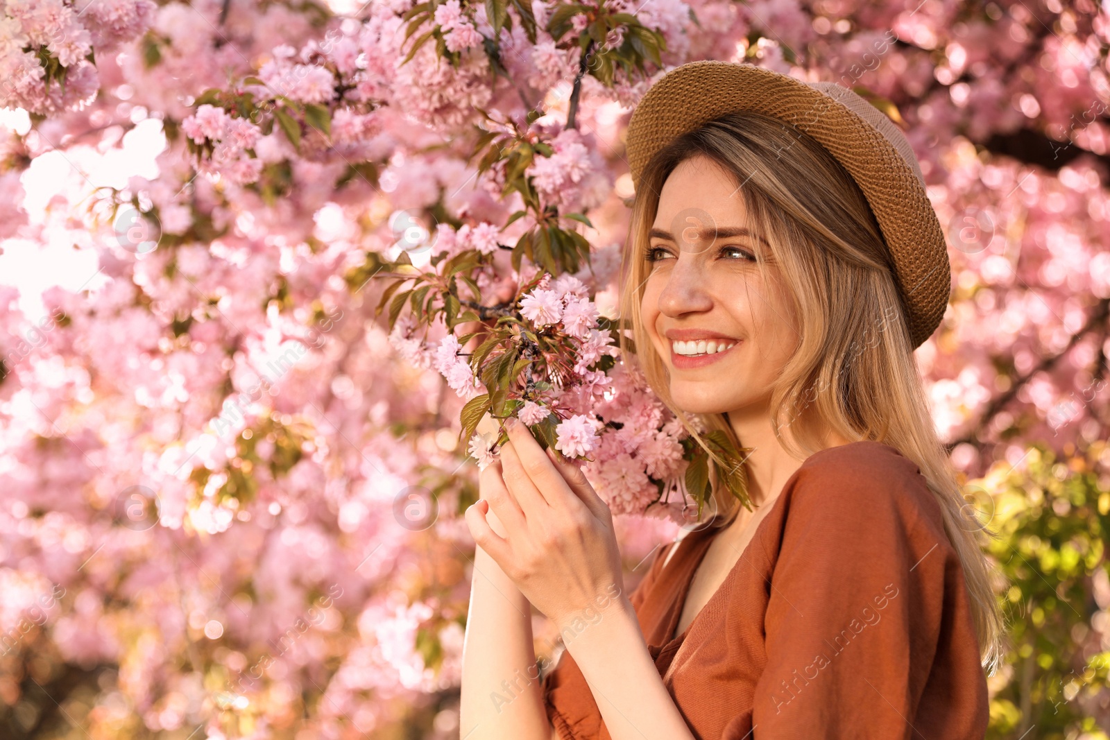 Young woman wearing stylish outfit near blossoming sakura in park. Fashionable spring look Photo of Young woman wearing stylish outfit near blossoming sakura in park. Fashionable spring look