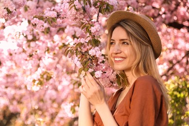 Young woman wearing stylish outfit near blossoming sakura in park. Fashionable spring look Photo of Young woman wearing stylish outfit near blossoming sakura in park. Fashionable spring look