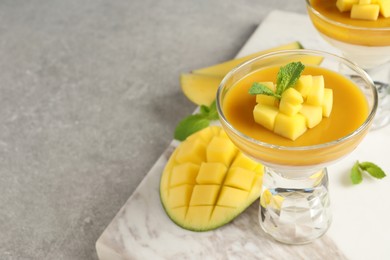 Delicious panna cotta with mango coulis and fresh fruit pieces on light grey table. Space for text Photo of Delicious panna cotta with mango coulis and fresh fruit pieces on light grey table. Space for text