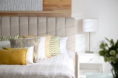 Photo of Comfortable bed with soft color pillows indoors