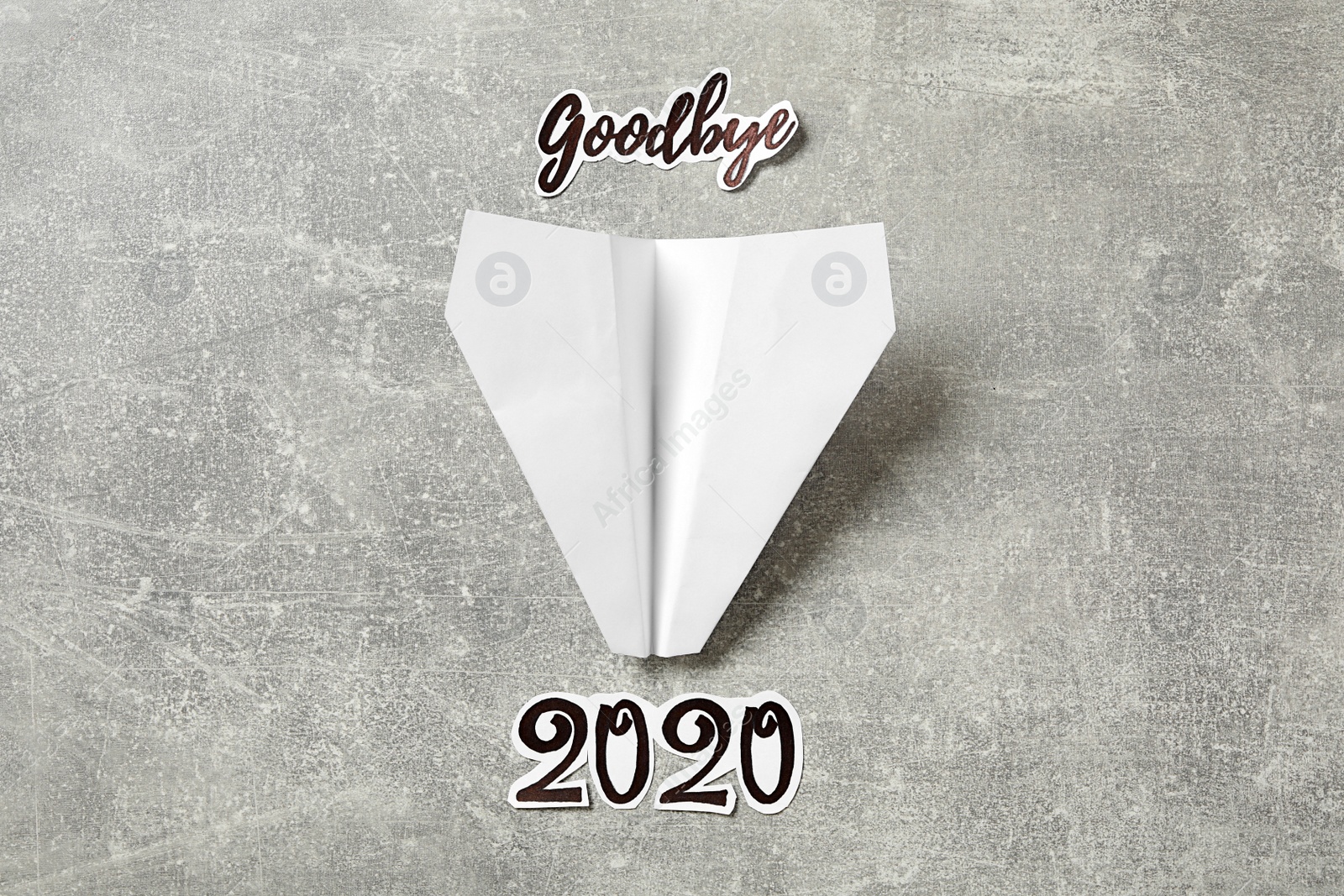 Text Goodbye 2020 and paper plane on grey background, flat lay Photo of Text Goodbye 2020 and paper plane on grey background, flat lay
