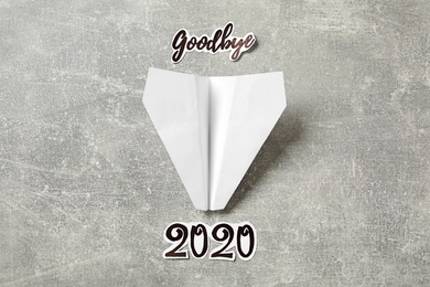Text Goodbye 2020 and paper plane on grey background, flat lay Photo of Text Goodbye 2020 and paper plane on grey background, flat lay