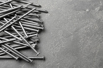 Pile of metal nails on grey stone background, flat lay. Space for text Photo of Pile of metal nails on grey stone background, flat lay. Space for text