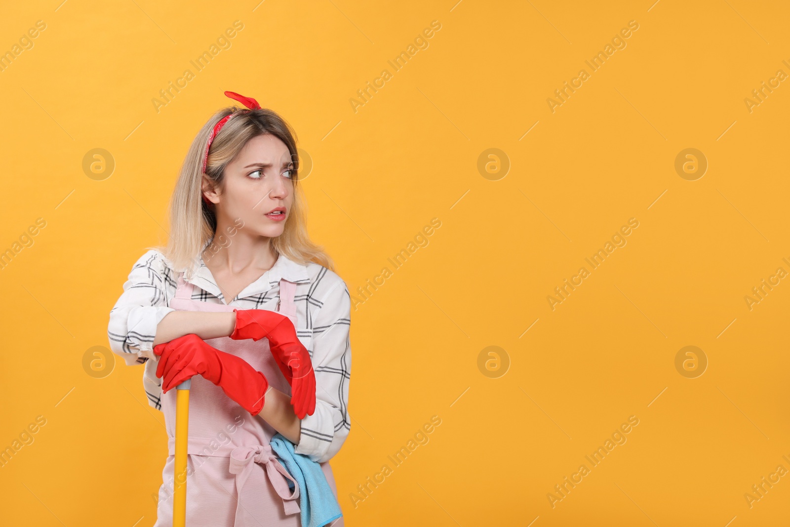 Young housewife with broom on yellow background. Space for text Photo of Young housewife with broom on yellow background. Space for text