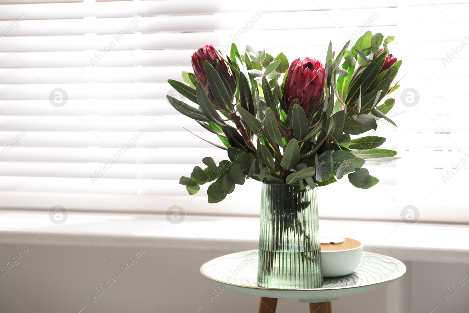 Vase with bouquet of beautiful Protea flowers on table indoors Photo of Vase with bouquet of beautiful Protea flowers on table indoors