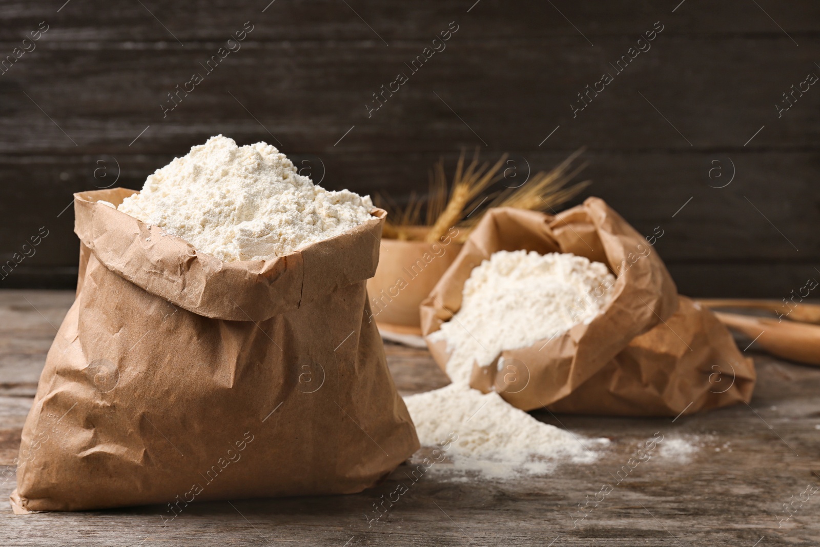 Paper bags with flour on wooden table Photo of Paper bags with flour on wooden table