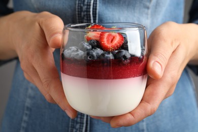 Woman holding glass dish delicious panna cotta with berries, closeup Photo of Woman holding glass dish delicious panna cotta with berries, closeup