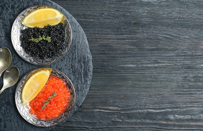 Plates with black and red caviar on wooden background Photo of Plates with black and red caviar on wooden background