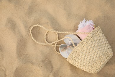 Beach bag with flip flops, towel and sunglasses on sand, top view. Space for text Photo of Beach bag with flip flops, towel and sunglasses on sand, top view. Space for text