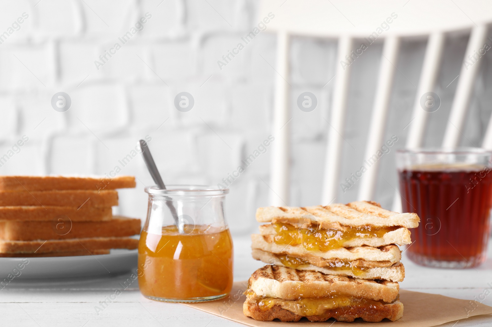 Tasty sandwiches with apricot jam and peanut butter for breakfast on white table Image of Tasty sandwiches with apricot jam and peanut butter for breakfast on white table