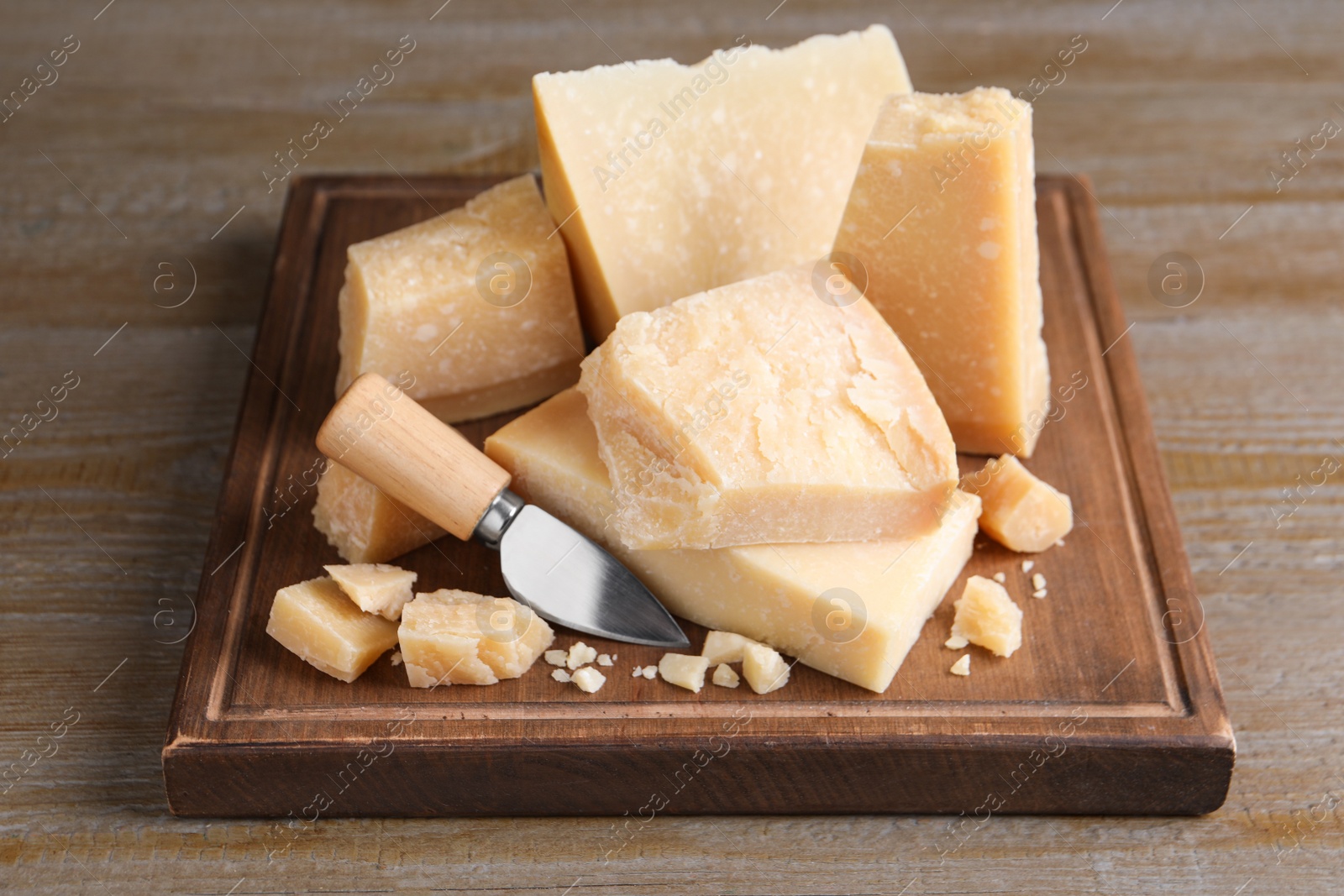 Delicious parmesan cheese with knife on wooden table Photo of Delicious parmesan cheese with knife on wooden table