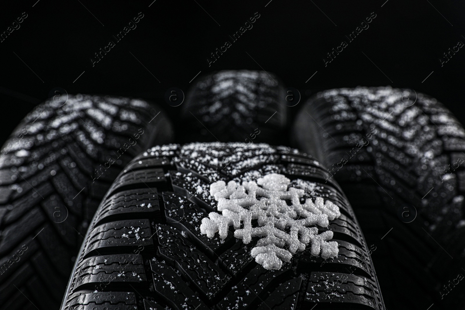 Set of new winter tires on black background, closeup Photo of Set of new winter tires on black background, closeup